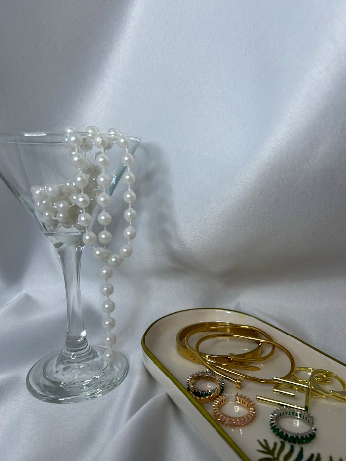 Sophisticated arrangement of pearls and gold jewelry on a white background.