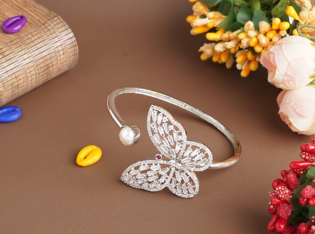 Stylish butterfly bracelet with pearl on a brown surface adorned by colorful beads and flowers.
